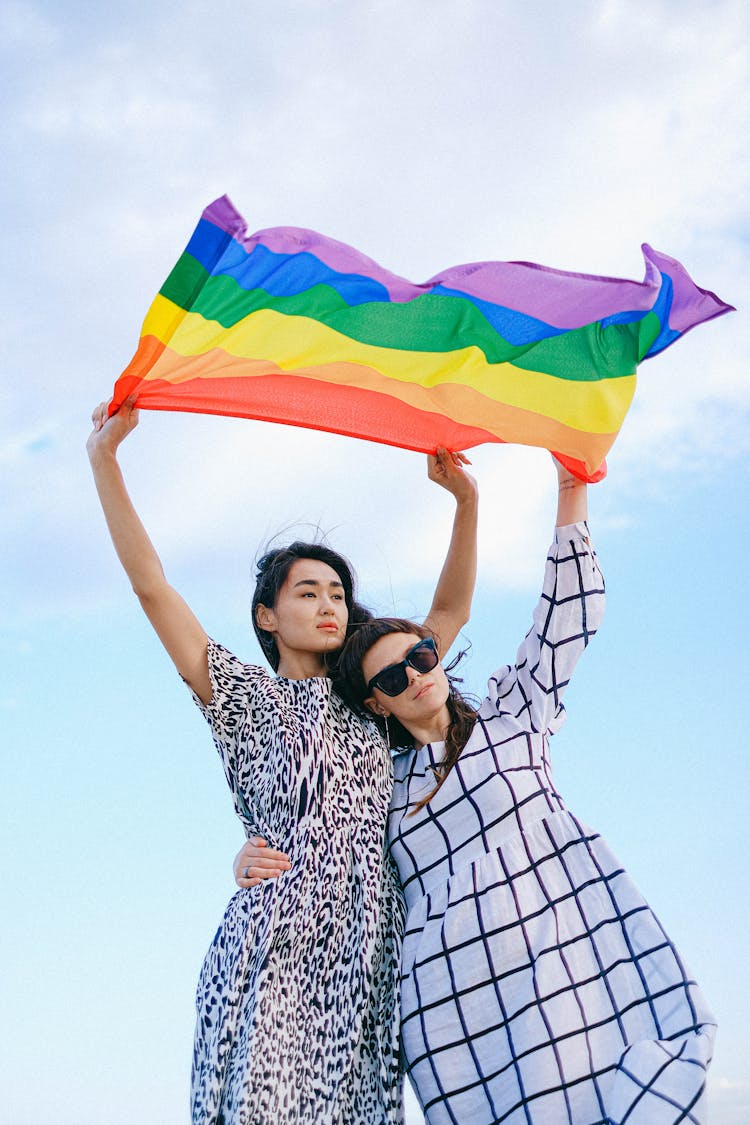 A Couple Waving A Rainbow Flag