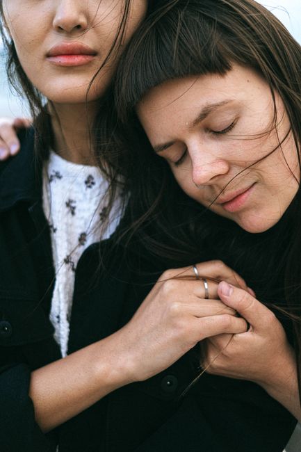 Close-up of two women embracing, eyes closed, showing affection and love.