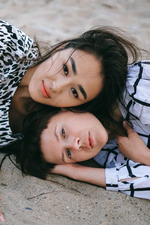 Free Two women intimately lying on a sandy beach, conveying love and connection. Stock Photo