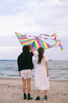 两个女人在沙滩上放着象征自由与爱的彩虹风筝