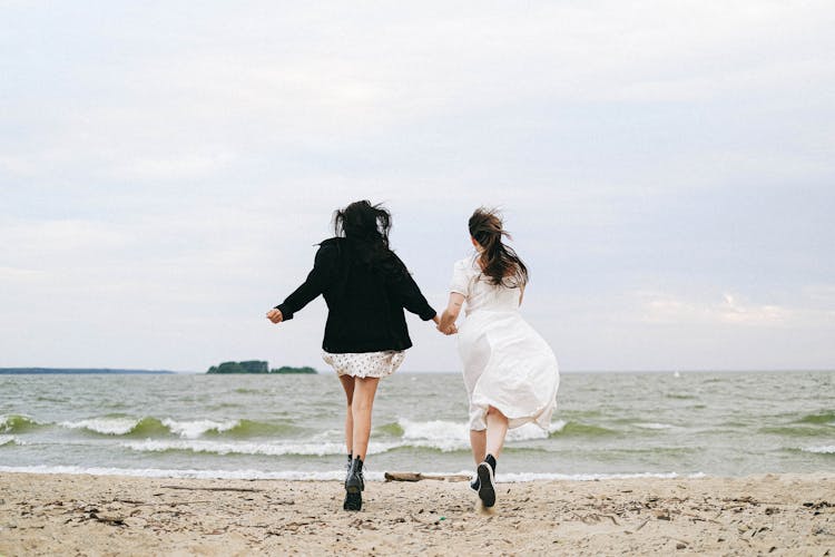 A Couple Running Together At The Beach