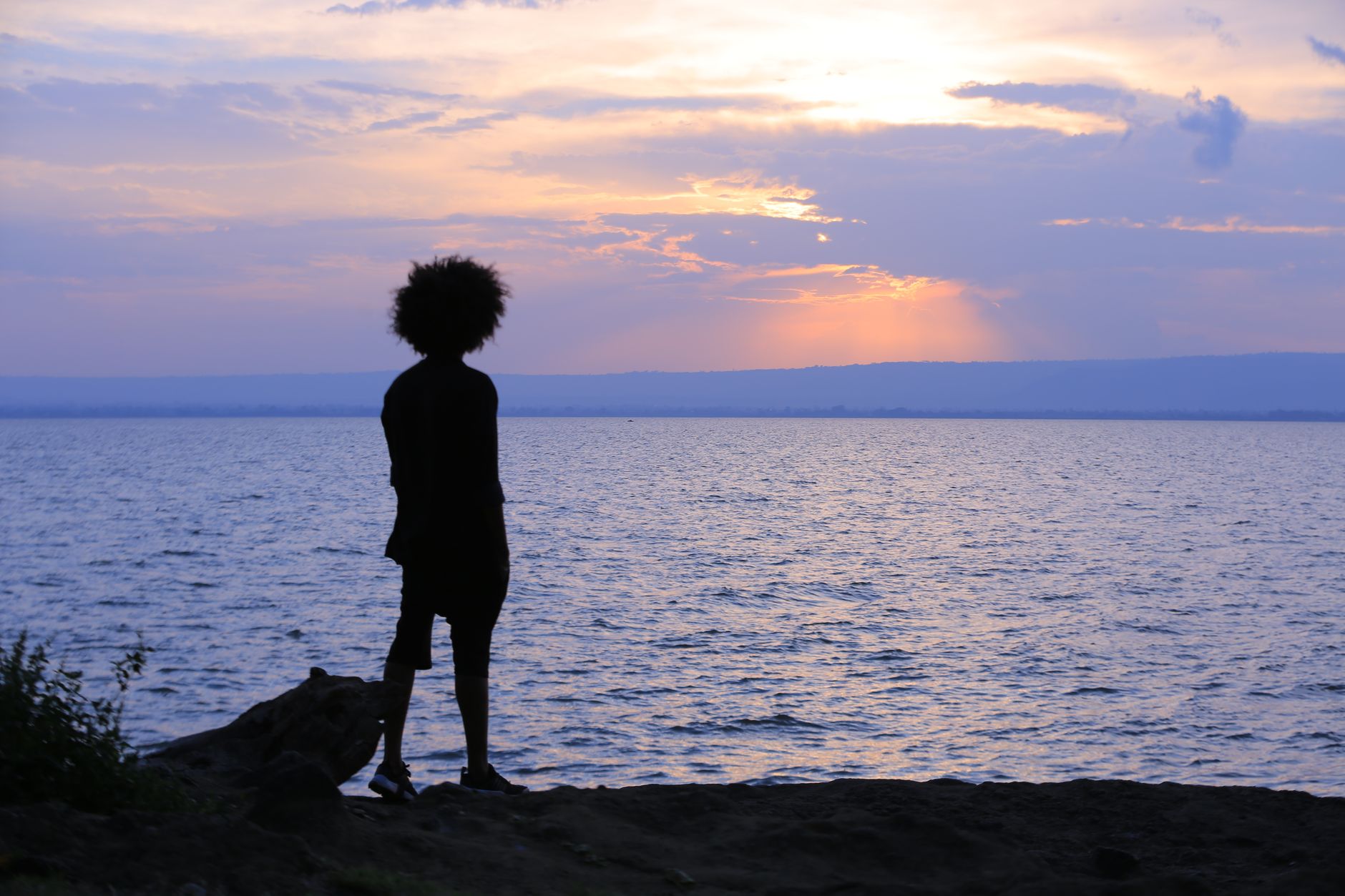 Silhouette of a person standing by Lake Awassa at sunset, capturing tranquility and nature's beauty.