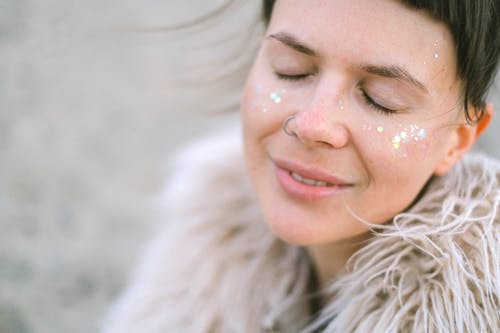 Happy woman with glitter on cheeks and closed eyes