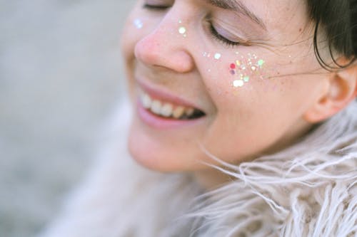 Side view of female with glitter laughing and enjoying moment with closed eyes