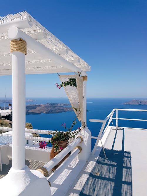 Comfortable white balcony rounded with peaceful turquoise scenery of wide ocean and clear sky on resort