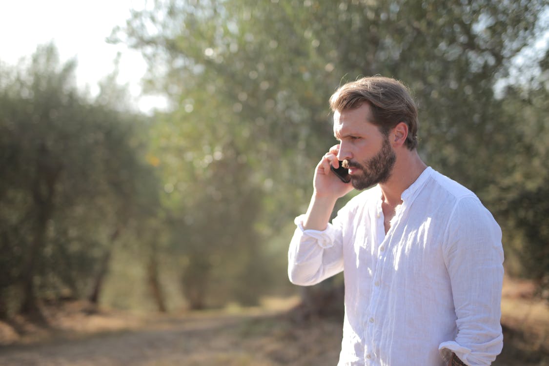 Man in White Long Sleeves Talking on Phone 