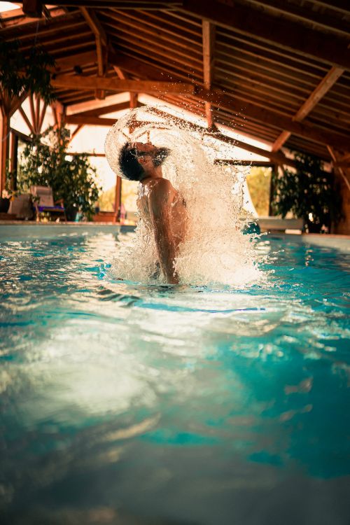Free Side view of young male surfacing from water in swimming pool while spending weekend in house Stock Photo