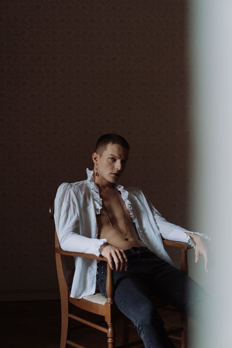 Man In Blue Dress Shirt And Blue Denim Jeans Sitting On White Chair