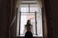 Woman in Black Tube Dress Standing Near Window