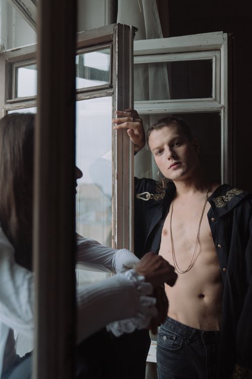 Free Elegant portrait of a young man by a window, showcasing fashion and subtle expression. Stock Photo