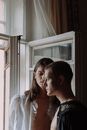 Woman in White Long Sleeve Shirt Standing Beside Window
