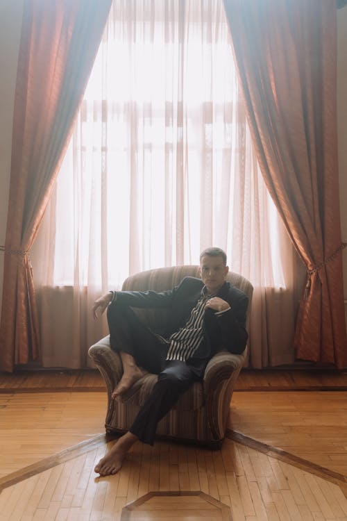 Man in Black Jacket Sitting on Brown Sofa Chair