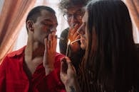 Man in Red Dress Shirt Smoking Cigarette Beside Woman in Red Dress