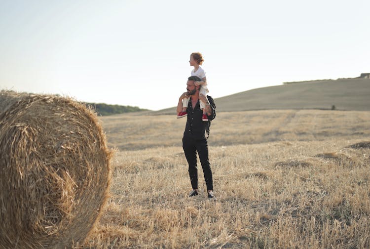 Father Giving Child Piggyback Ride Out In Field