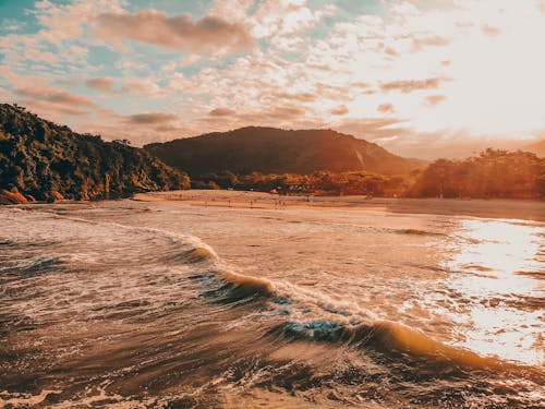 Scenic view of waving sea near hilly green coast