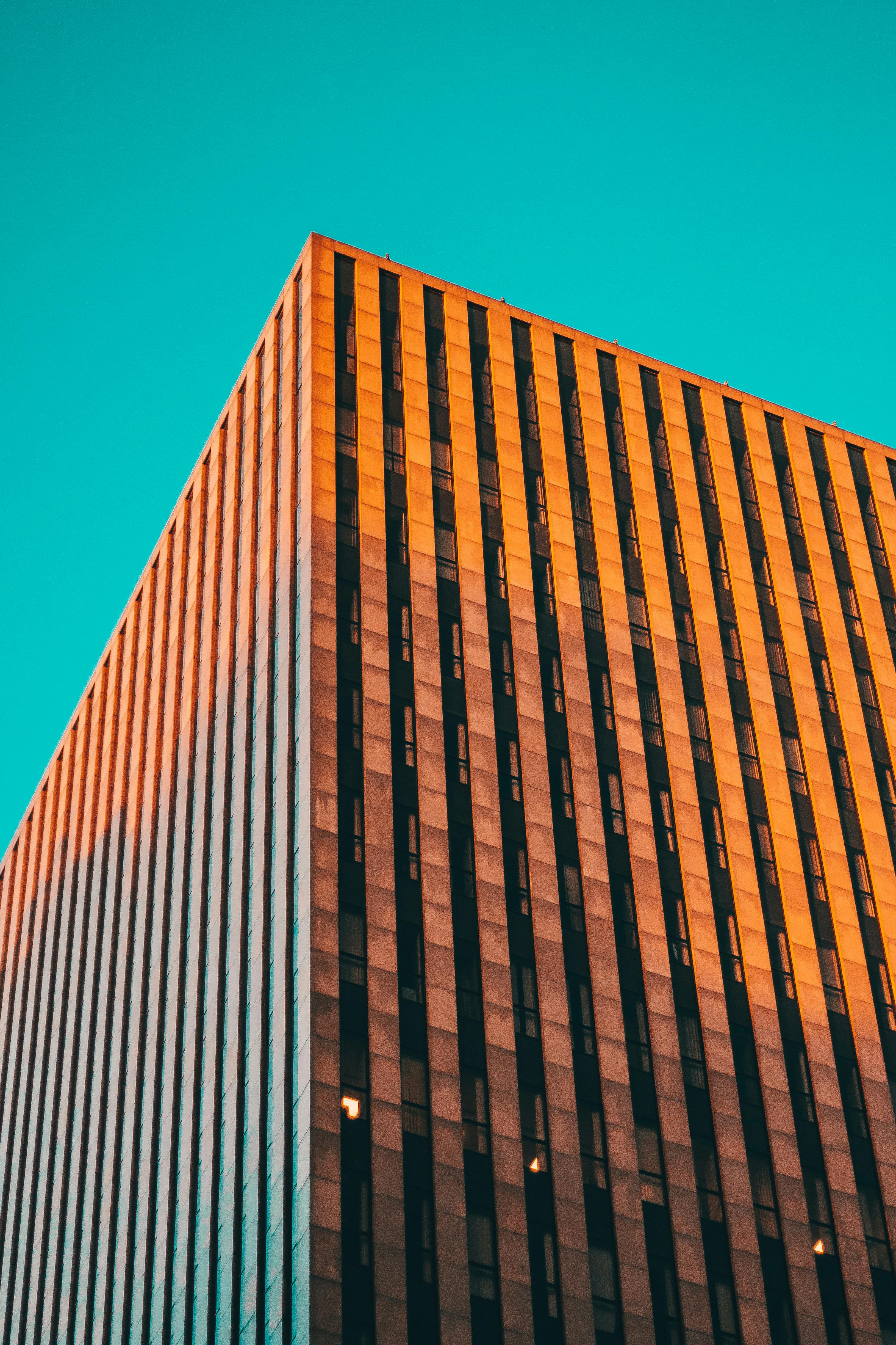 Free Low angle view of a modern skyscraper with a striking facade against a vibrant blue sky. Stock Photo