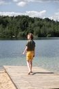 Back View of a Boy Walking on Wooden Jetty