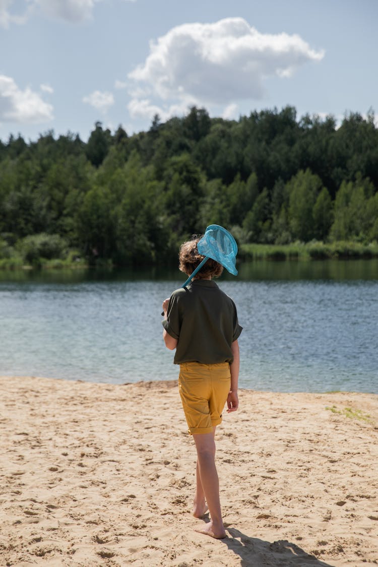 Boy With Net Walking On Beach