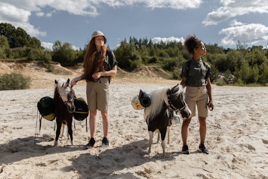 Two scout girls with ponies on a sandy terrain under a bright sky.