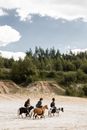 People Sitting on Brown Dirt Road Near Green Trees Under White Clouds and Blue Sky during