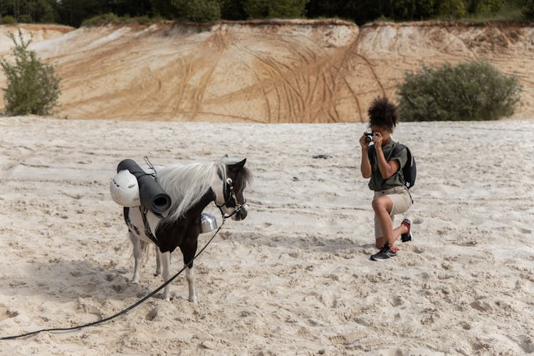 Woman Taking Picture Of Donkey In Desert