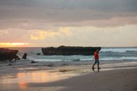Woman in Red Shirt and Black Shorts Standing on Seashore
