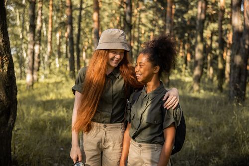 Free Two friends in a forest enjoying a sunny day, dressed in scout uniforms, embodying friendship and nature. Stock Photo