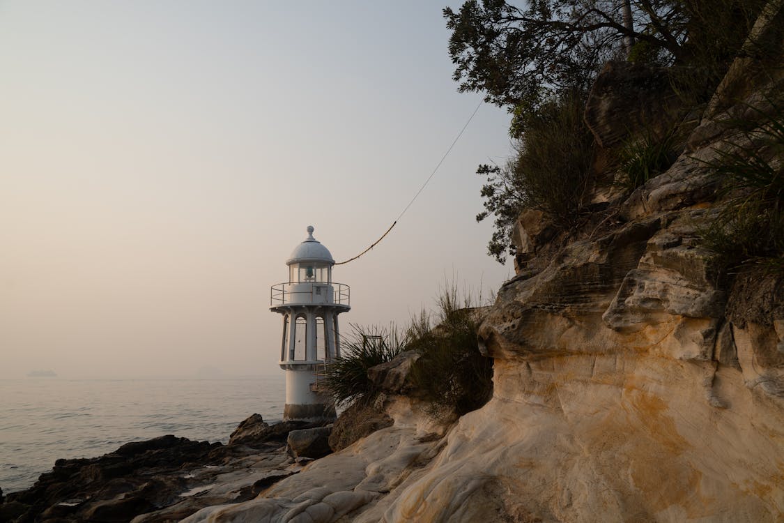 Free White Lighthouse on Rock Formation Near Body of Water Stock Photo
