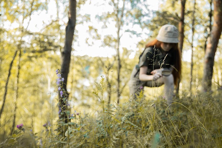 Scout Girl Walking In Grass With Wildflowers With Magnifying Glass