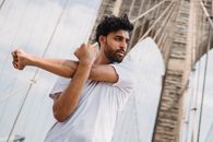Man in White T-shirt Standing on Wooden Bridge