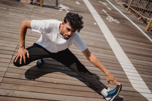 Free Athletic man performing dynamic stretches outdoors to start a workout session. Stock Photo