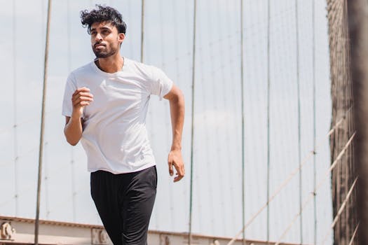 Active young man jogging on a suspension bridge in an urban setting, promoting healthy lifestyle and fitness.