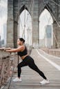 一名穿着运动服的女人白天在布鲁克林大桥上伸展，展现了城市健身的风貌
