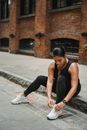 Woman in Black Tank Top and Black Leggings Sitting on Concrete Floor