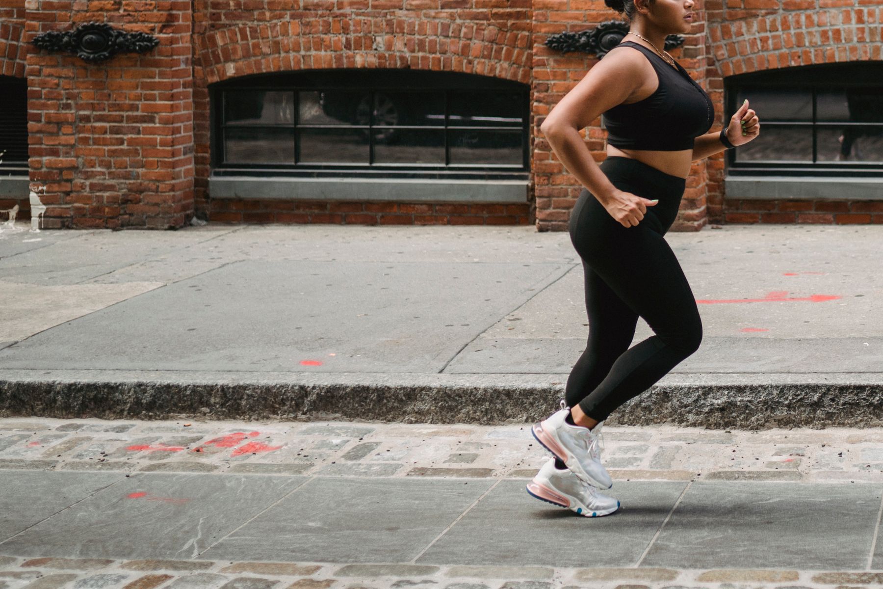 Woman running through a modern city street in performance wear