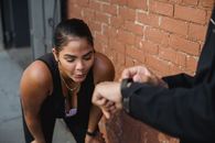 Woman in Black Tank Top Leaning on Brown Brick Wall