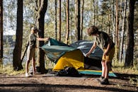 阳光普照的森林湖边，两名少年搭起帐篷，享受户外露营的乐趣