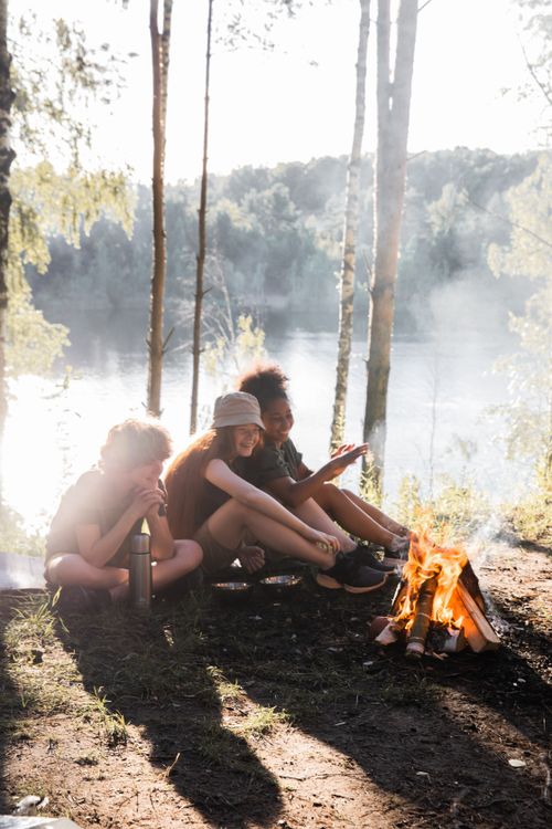 Free Group of children enjoying a campfire by a serene lake surrounded by nature. Stock Photo