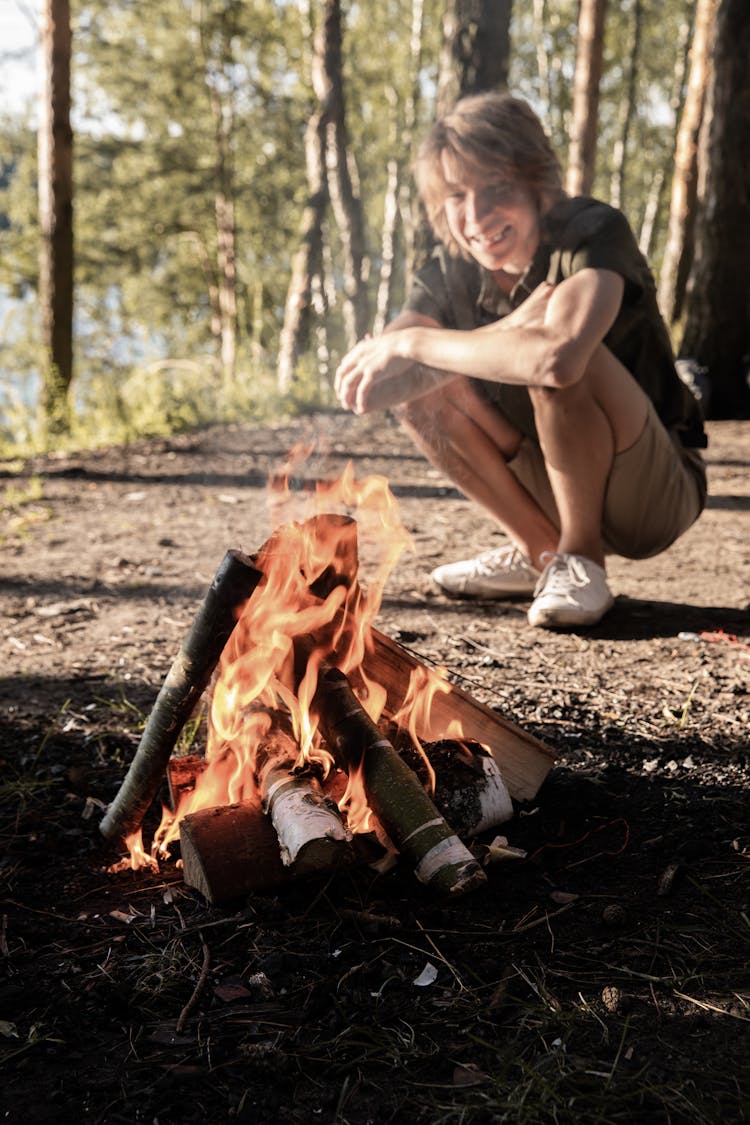 Boy Crouching By The Fire