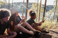 一群青少年在阳光明媚的森林里烤棉花糖，享受夏日时光