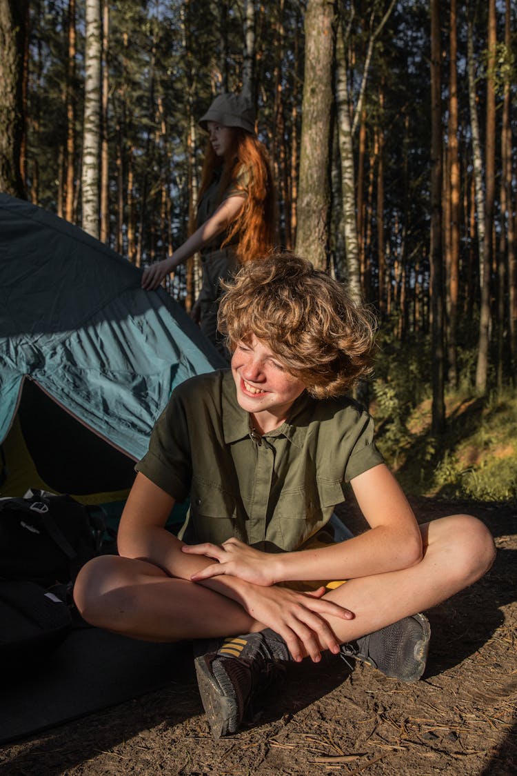 Teenagers On An Adventure In A Forest Setting Up A Tent 