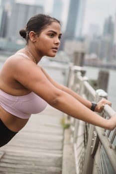 Woman stretching by the waterfront against a city skyline, exuding focus and determination.