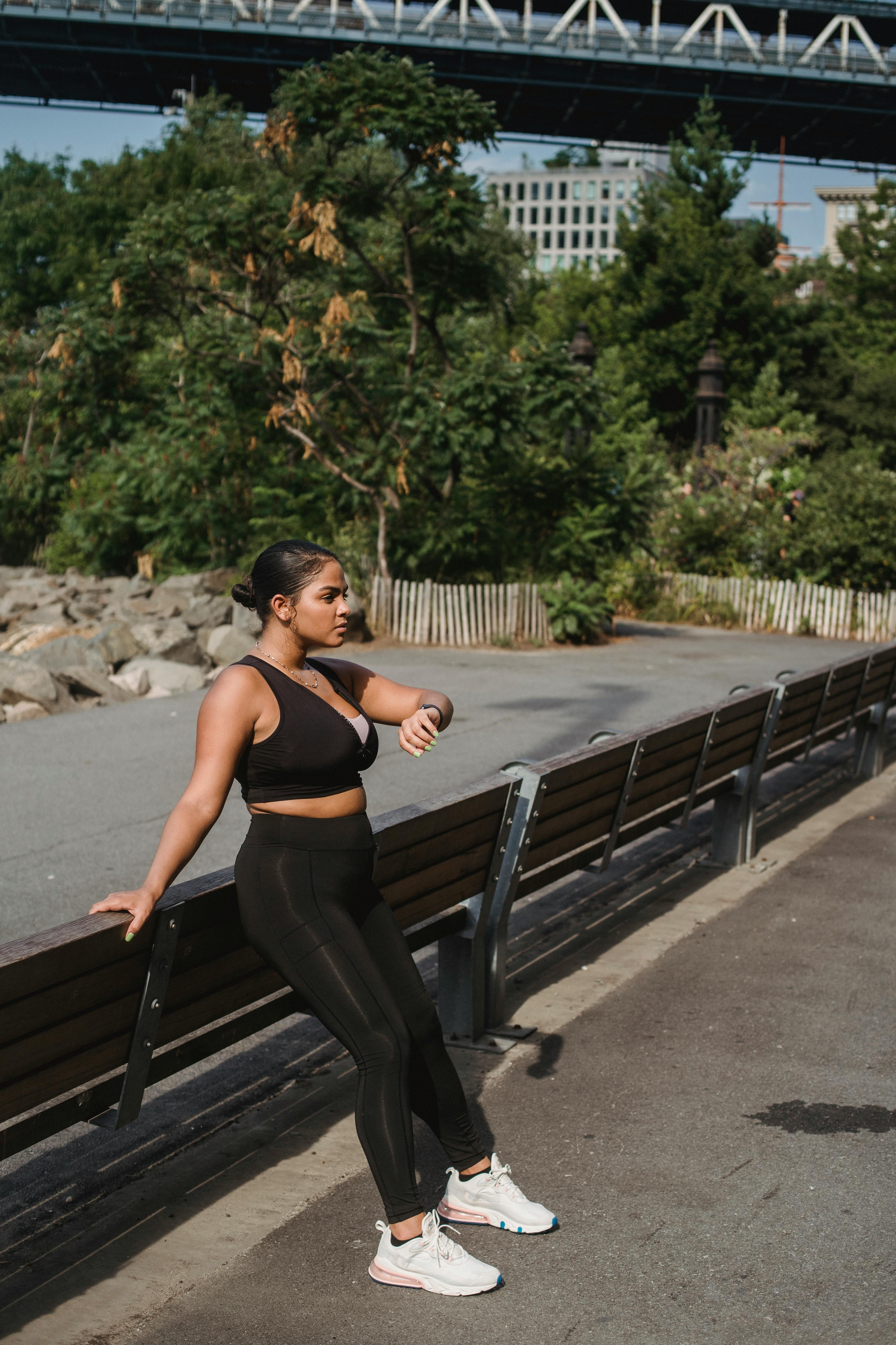 一名穿着运动服的年轻女子在城市公园附近的桥下检查智能手表