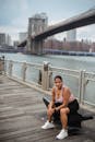 Woman in Black Tank Top Sitting on Wooden Dock