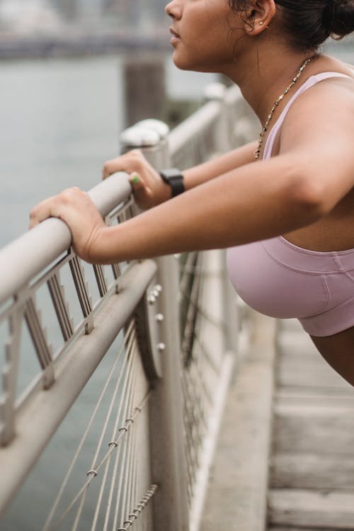 Free Woman in White Sports Bra and White Shorts Holding on Gray Metal Railings Stock Photo