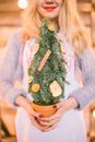 室内，一位金发女人拿着节日迷你松树和橙片