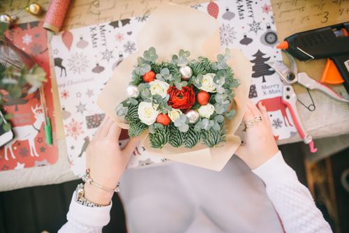 Free Overhead view of a holiday-themed bouquet arrangement with seasonal decorations and gift wrap. Stock Photo