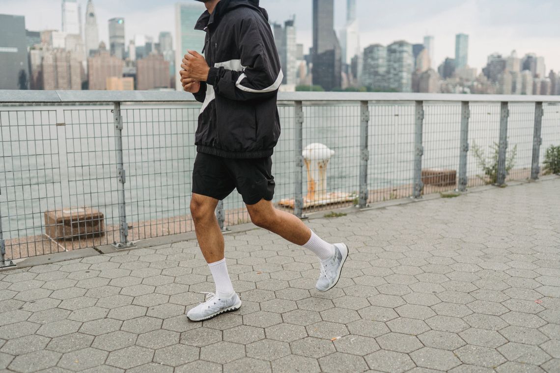 Man running along an urban waterfront in sportswear