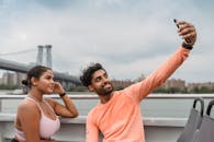 一对开朗的夫妇在风景如画的城桥背景下乘船自拍