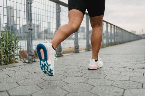 Free Close-up of legs jogging outdoors with urban backdrop, wearing athletic shoes. Stock Photo